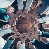 Group of office workers making a circle with their fist to celebrate unity and excitement.